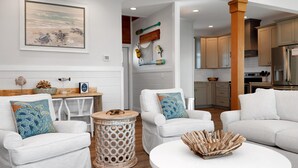 A modern living room with white sofas, a round coffee table, and a painting of sea turtles. - The Lazy Turtle (Port St. Joe)