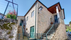 Un edificio de piedra con una puerta verde, una escalera y un pequeño balcón.