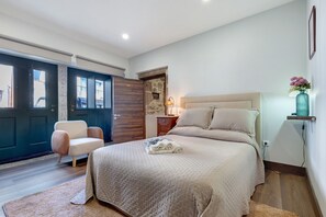 Une chambre à coucher avec un lit, une chaise, une table de chevet, une lampe et une porte.