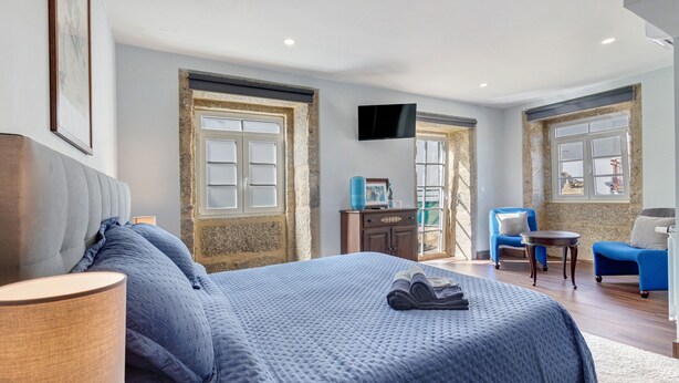 Un dormitorio con una cama grande, televisión, escritorio y dos sillas.