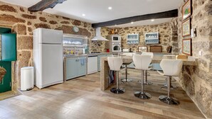 Una cocina con paredes de piedra, techo de madera y una barra con taburetes.