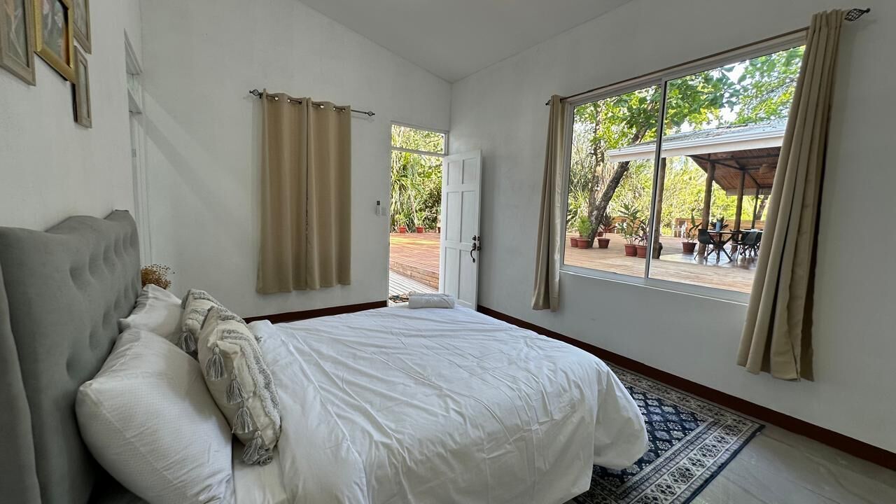 A bedroom with a bed, curtains, a window, and a view of the outdoors.