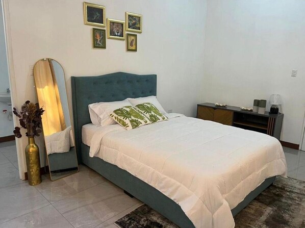 Une chambre à coucher avec un lit, une table de chevet, un miroir et des œuvres d’art murales.