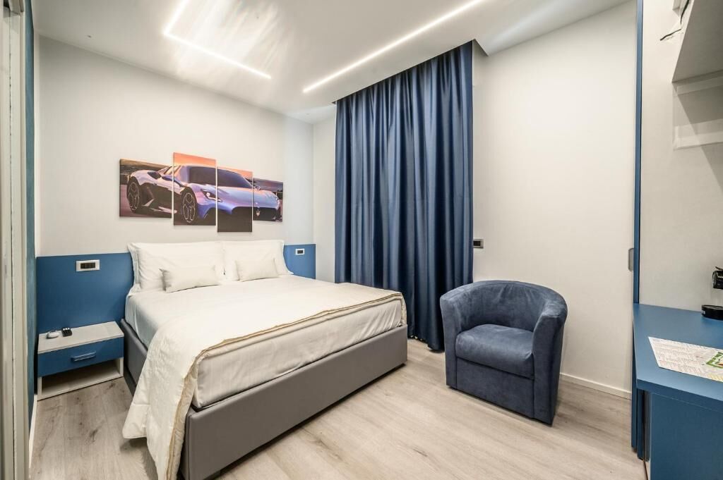 Een moderne hotelkamer met een bed, een stoel, een bureau en een schilderij aan de muur.