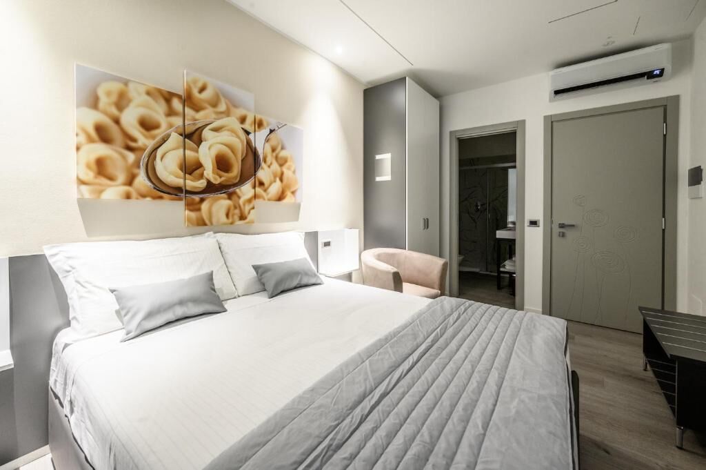 Une chambre d’hôtel moderne équipée d’un grand lit, d’une chaise, d’un bureau et d’un climatiseur fixé au mur.