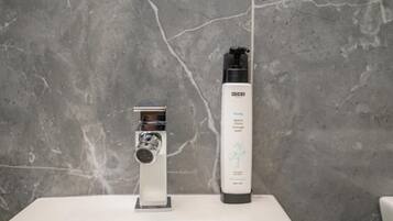 A bathroom with a modern sink, a chrome faucet, and a bottle of hygiene product.