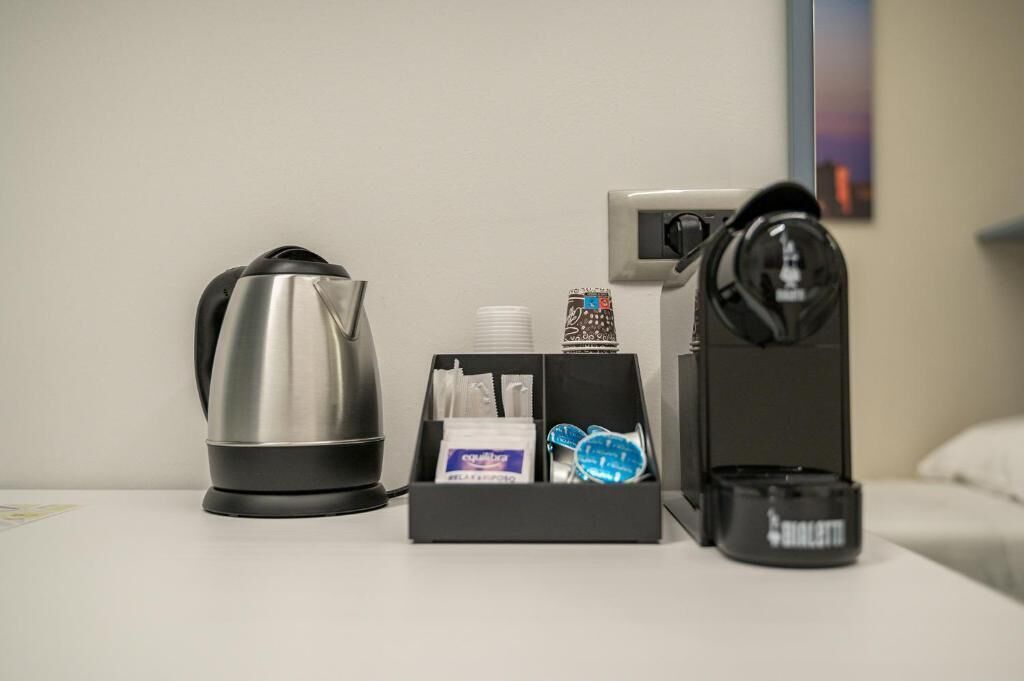 Una camera d'albergo con una macchina del caffè, un bollitore e un set di articoli da toilette.