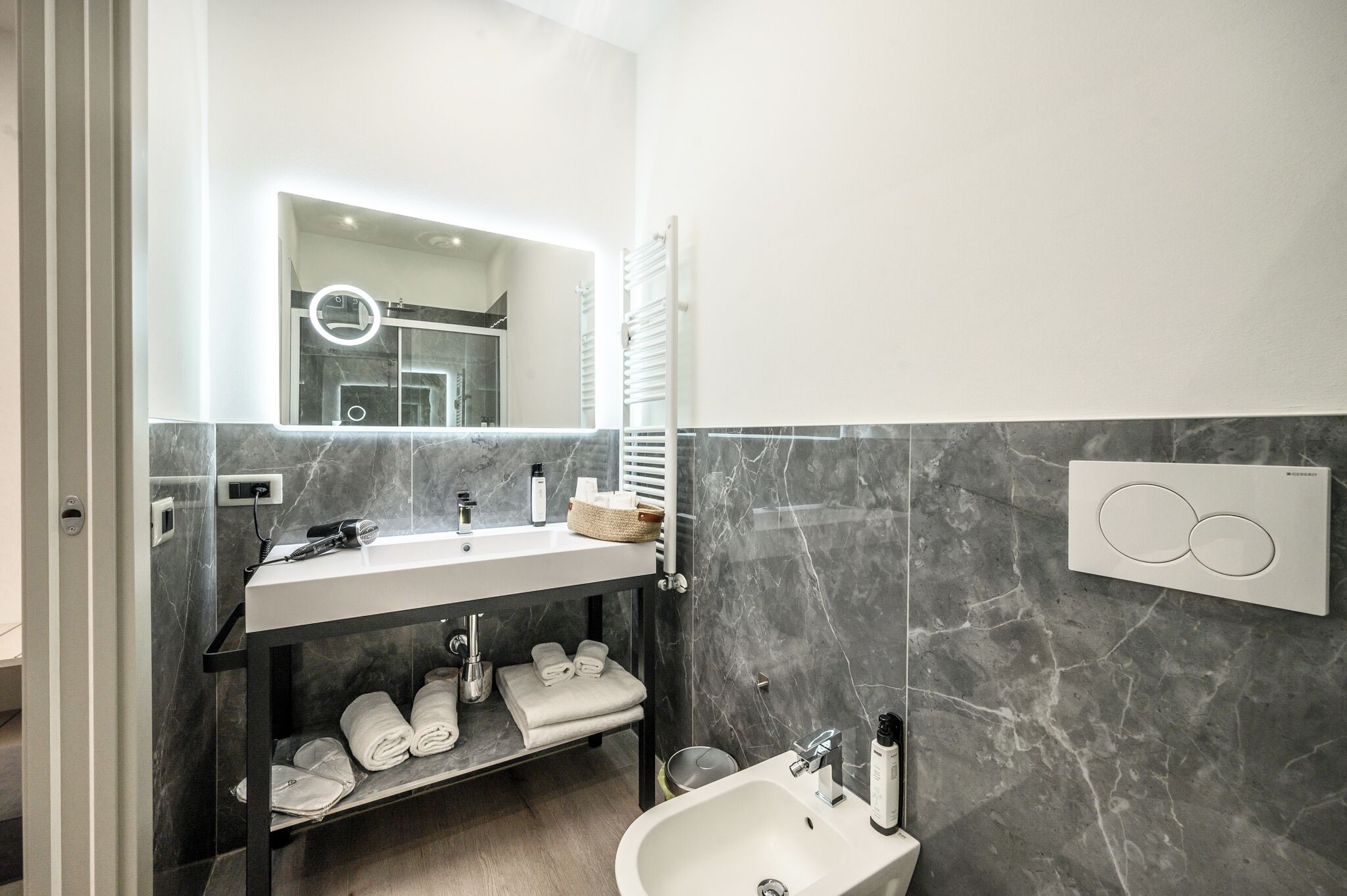 A modern bathroom with a marble vanity, a built-in towel rack, and a wall-mounted heater.