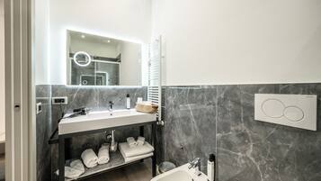 A modern bathroom with a marble vanity, a built-in towel rack, and a wall-mounted heater.