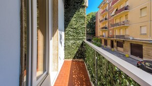 Un balcon étroit doté d’un sol carrelé, d’un mur végétal vertical et offrant une vue sur les bâtiments voisins.