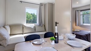 Ein modernes Zimmer mit einer Couch, einem Esstisch gedeckt mit Tellern, Gläsern und einer Flasche.