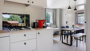 Eine moderne Küche mit Gasherd, einer roten Kaffeemaschine und einem Essbereich mit Tisch und Stühlen.