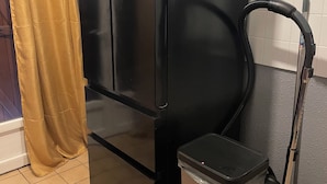 Kylpyhuoneessa on musta kaappi, roskakori ja pölynimuri.