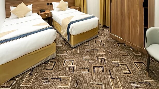 A hotel room with two beds, a wardrobe, a chair, and an air conditioning unit.