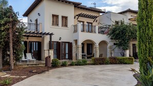 Ein zweistöckiges Haus mit Terrasse, Sitzgelegenheiten im Freien und einem gepflegten Garten.