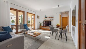 Ein modernes Wohnzimmer mit Sofa, Couchtisch und Fernseher, verbunden mit einem Balkon mit Aussicht.