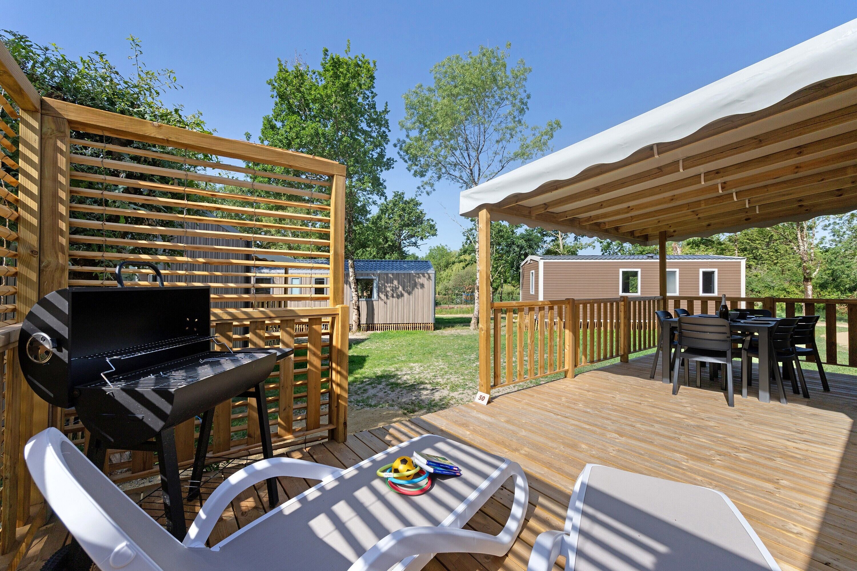 An outdoor deck with a grill, chairs, and a table.
