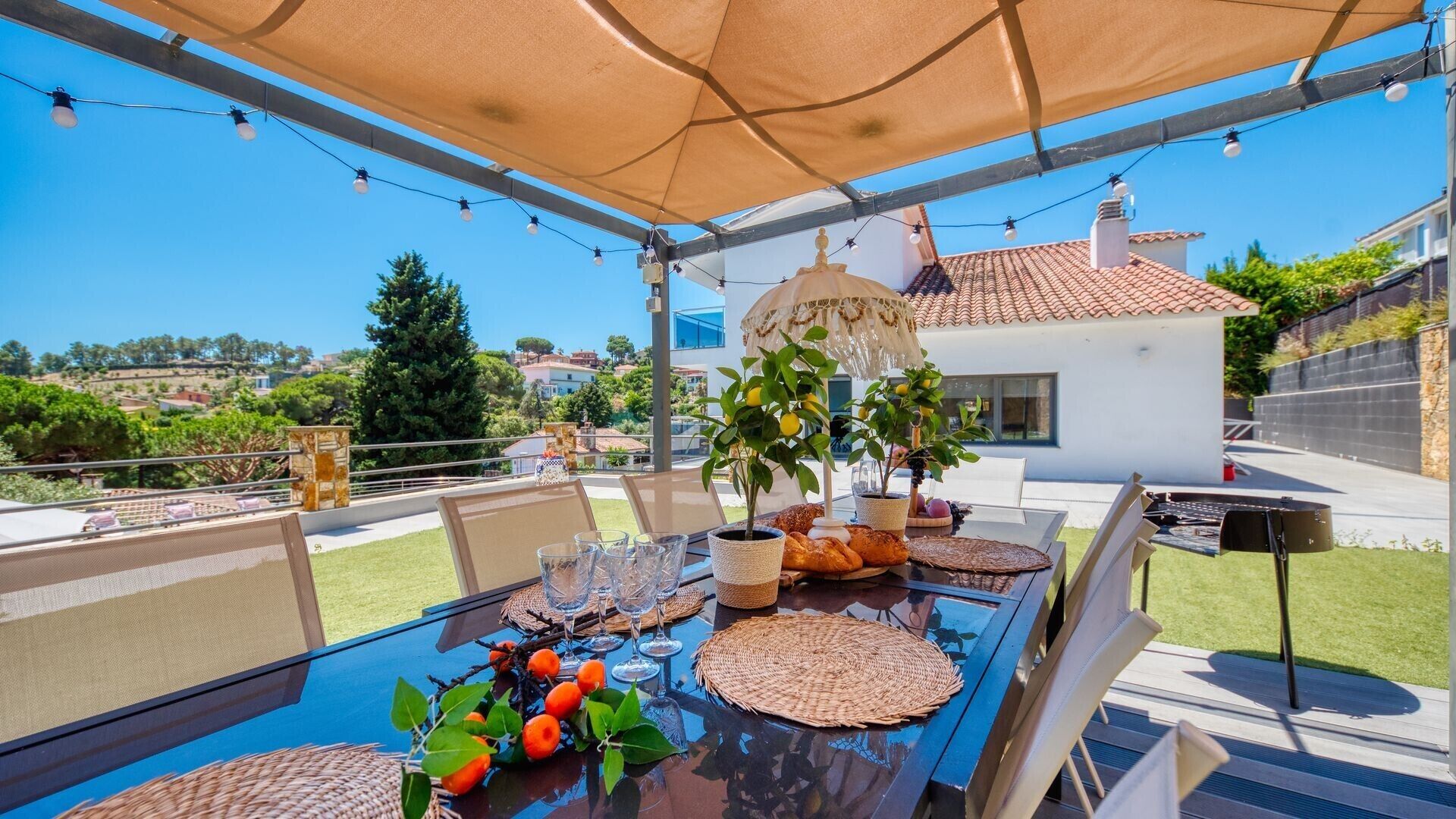 An outdoor dining area with a table set for four, surrounded by chairs, under a canopy.