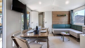 Uma área de refeições moderna, com uma mesa posta para quatro, um banco embutido e uma televisão na parede.