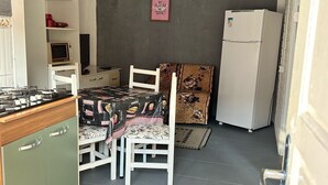 Une cuisine compacte comprenant un coin repas, un four à micro-ondes, un réfrigérateur et une petite table avec des chaises.