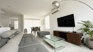 A modern living room with a sofa, glass coffee table, and a TV mounted on the wall. - Blue Villas by Host Ecuador (Santa Elena)