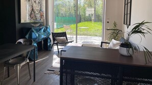 A modern interior with a dining area, a large window with a view of a garden, and a painting on the wall. - Les Charmilles - A romantic and luminous escape (Gien)