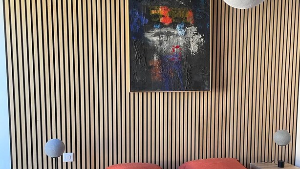 A modern bedroom with a striped wooden wall, a large abstract painting, a bed with red bedding, and two bedside lamps. - Les Charmilles - A romantic and luminous escape (Gien)