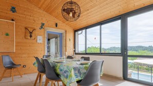 Comedor con una mesa dispuesta para cuatro, paredes de madera y un ventanal con vistas.