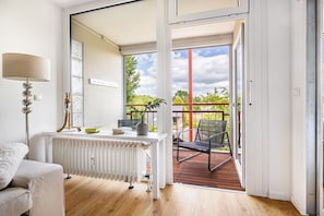 A modern interior with a white radiator, a lamp, and a view of an outdoor deck with a chair. - Luxurious Small Coastal Nest Apartment Directly on Lake Steinhude (Wunstorf)