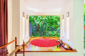 A room with a wooden bench, a red flower arrangement, and a wall with tropical plants. - Villa Jalamati - 3 BDR Luxury Escape, Prime Location (Kerobokan Kelod, Kec. Kuta Utara, Kabupaten Badung)