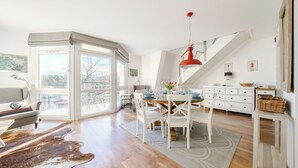 A modern dining area with a glass table, white chairs, and a red pendant light. - Apartamenty Sun & Snow Villa Mistral (Świnoujście)