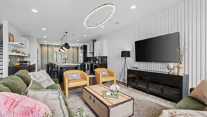Un salon moderne comprenant un canapé, des fauteuils, une table basse et un téléviseur.