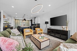 Una sala de estar moderna con un sofá, sillones, una mesa de centro y un televisor.