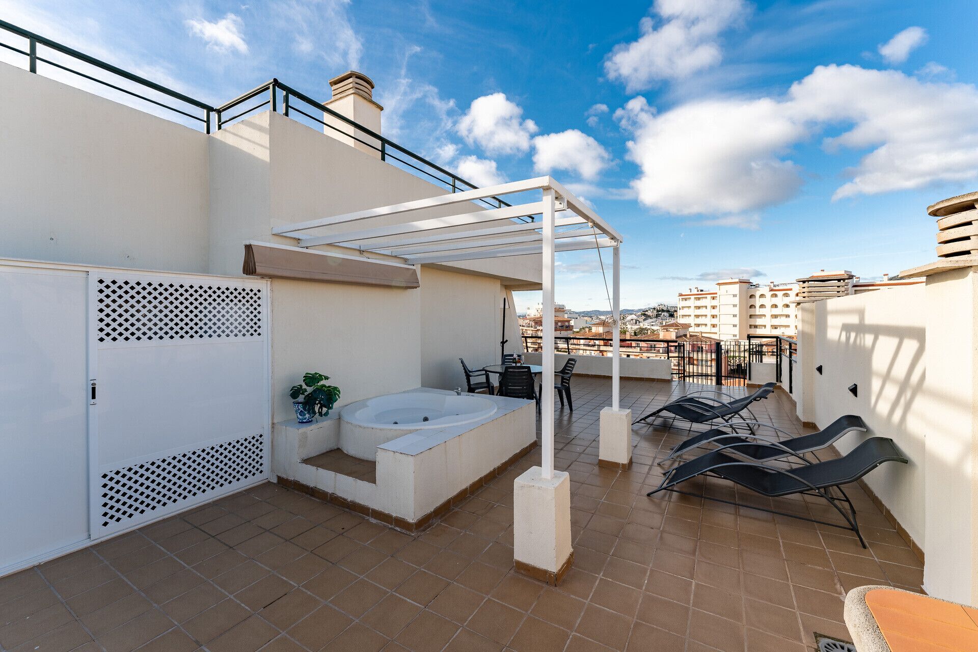 Une terrasse sur le toit dotée d’un jacuzzi, d’un espace salon et d’une pergola.