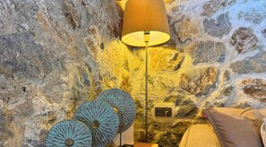 Interior de pared de piedra con una lámpara y platos decorativos.