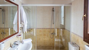 Un baño con ducha acristalada, lavabo, inodoro y espejo.