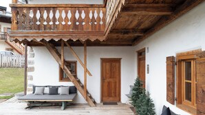 A wooden balcony with a railing, a wooden staircase, a door, and a small Christmas tree. - Chalet Greis by My Villa Collection (Cortina d'Ampezzo)