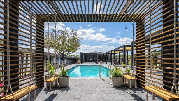 A pool area with a pergola structure, potted plants, and a clear view of the sky. - 3BR apartment with heated pool near Disney (Kissimmee)