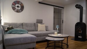 Un salon moderne avec un canapé gris, une table basse ronde et une cheminée.