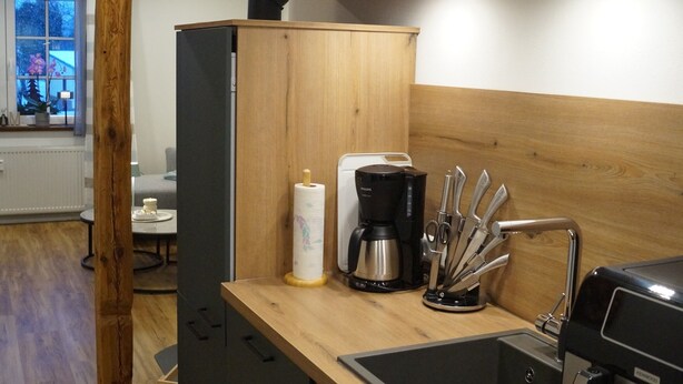 Une cuisine moderne dotée d’un plan de travail en bois, d’une machine à café, d’un bloc à couteaux et d’un four encastré.