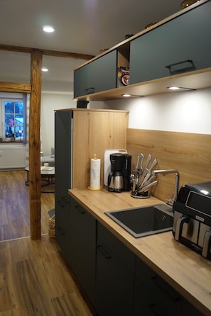 Une cuisine moderne dotée d’un plan de travail en bois, d’une machine à café, d’un bloc à couteaux et d’un four encastré.