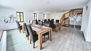 Un comedor con mesas y sillas de madera, una escalera y un mural en la pared.