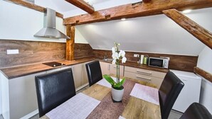 Una cocina compacta con vigas de madera, microondas y fregadero.