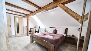 Un dormitorio con techo de madera, una cama con manta roja, una mesita de noche y un escritorio con silla.