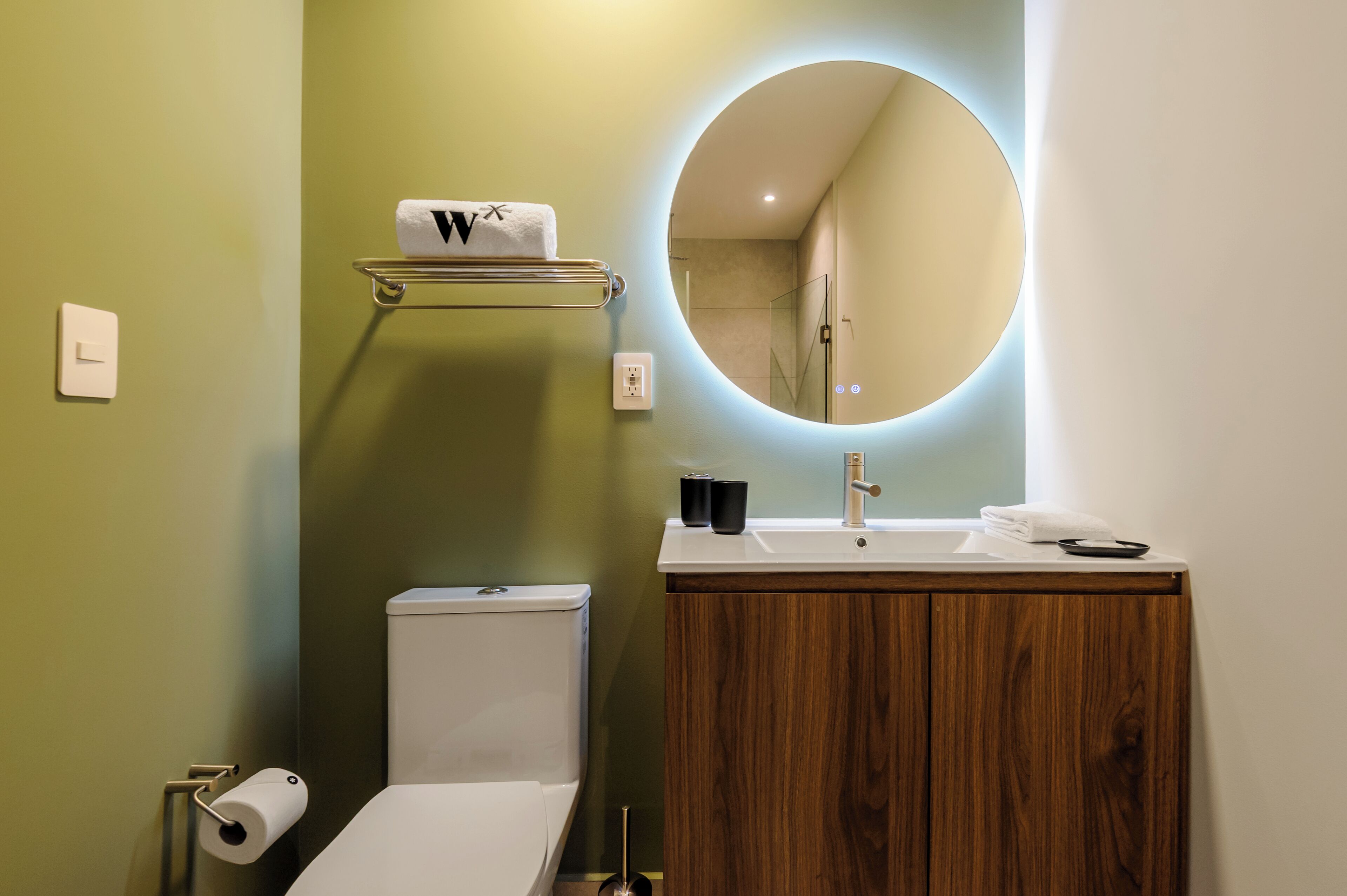 A modern bathroom with a toilet, sink, and mirror.