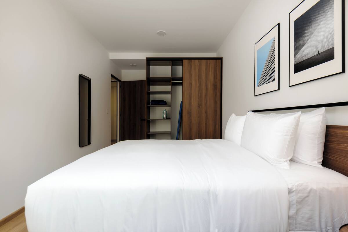 Een moderne hotelkamer met een groot bed, een garderobe en een kast met planken.