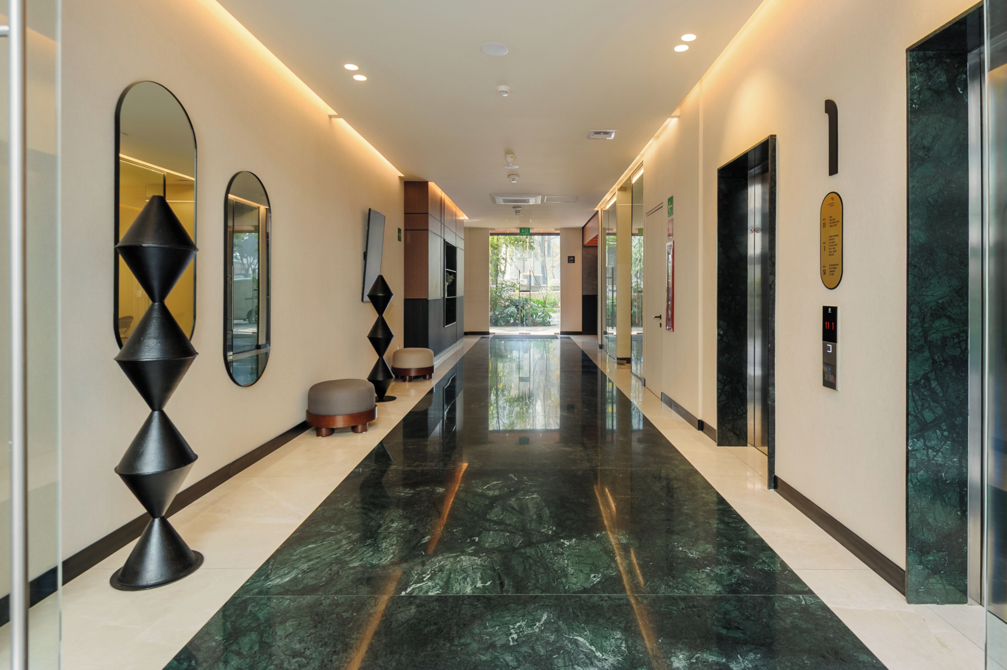 Un pasillo moderno de hotel con piso pulido, una larga galería y vista al exterior.