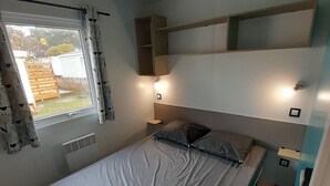 Pieni huone, jossa on yksi sänky, ikkuna, patteri ja sängyn yläpuolella oleva sisäänrakennettu hylly.