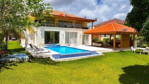 Une maison à deux étages avec une piscine, un patio couvert et une pelouse bien entretenue.
