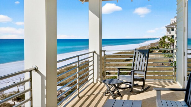 Un balcon fermé offrant une vue sur la plage et l’océan.